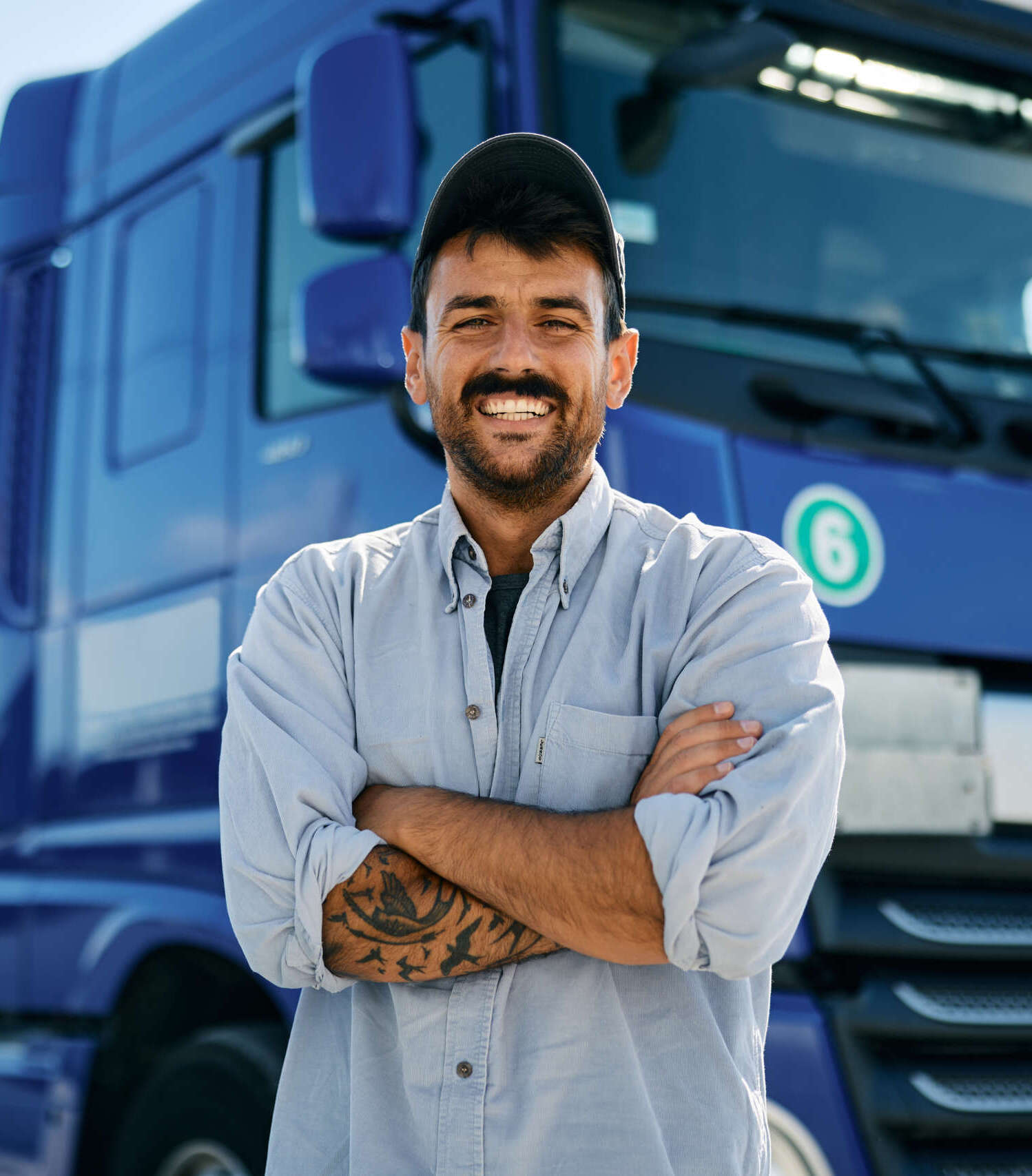 confident truck driver in front of his vehicle looking at camera.